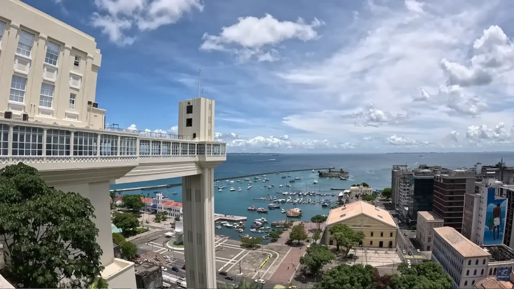 Vista panorâmica do Elevador Lacerda e do Mercado Modelo em Salvador, com barcos na Baía de Todos-os-Santos ao fundo.