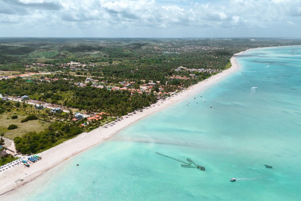 Vista aérea da praia de Maragogi em Alagoas com mar turquesa, um dos melhores roteiros de férias familiares no Nordeste.