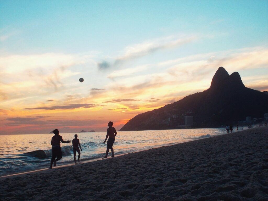 Jovens jogando futebol na praia de Ipanema ao pôr do sol no Rio de Janeiro, opção de roteiros de férias familiares com adolescentes.