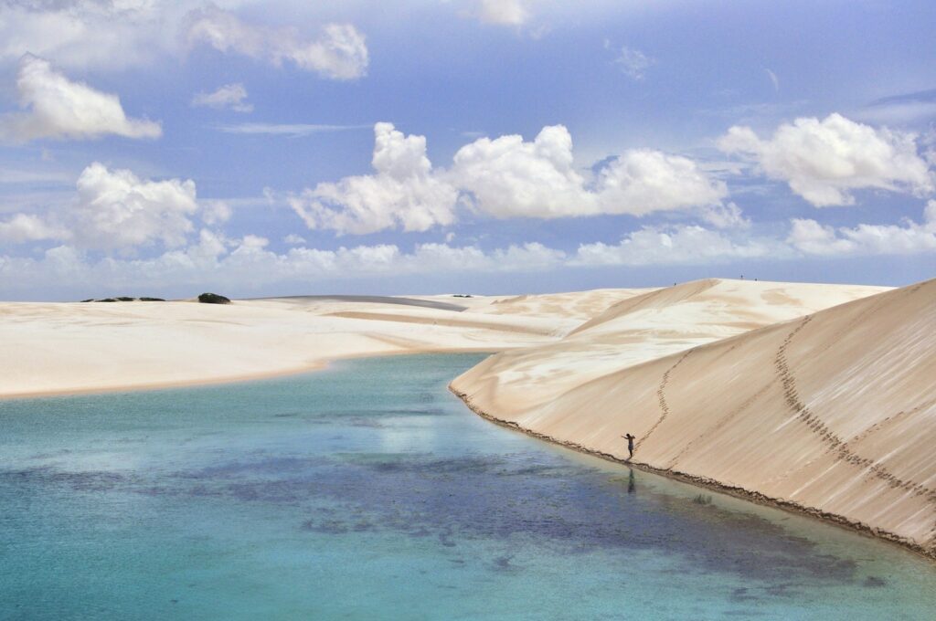 Turista caminhando nas dunas brancas e lagoas azuis dos Lençóis Maranhenses.