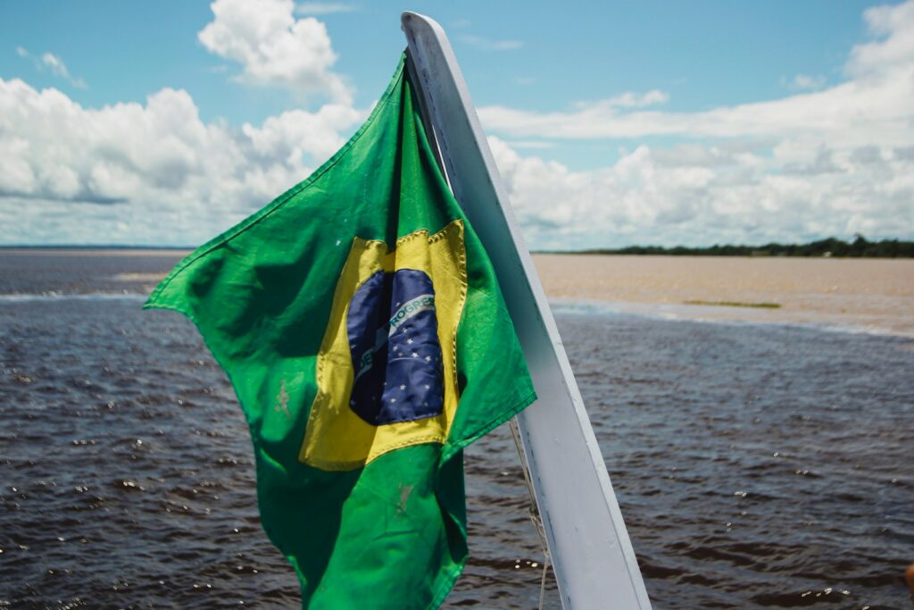 Bandeira nacional tremulando na popa de um barco durante passeio de turismo ecológico no Brasil nos rios.