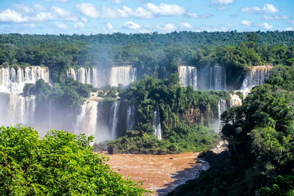 Vista panorâmica das impressionantes quedas d'água das Cataratas do Iguaçu cercadas por mata.