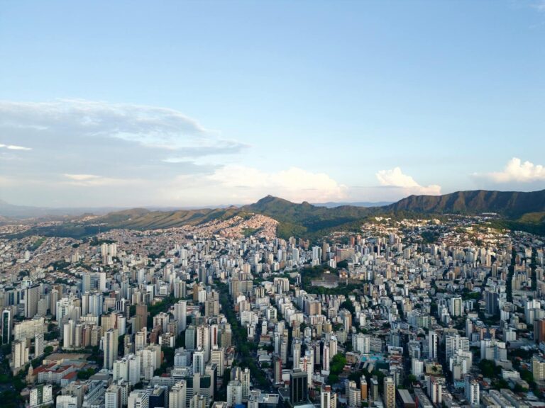 Vista aérea deslumbrante do horizonte de Belo Horizonte com colinas onduladas ao fundo, ao entardecer.