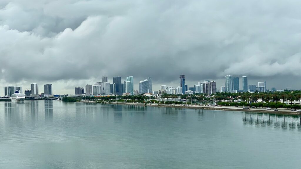Horizonte da cidade visto de um corpo d'água sob um céu nublado durante o dia.