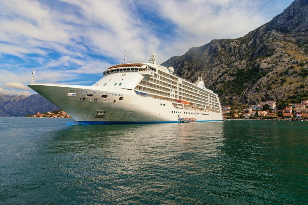 A cruise ship in the water with mountains in the background