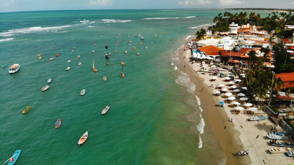 A stunning aerial view of Porto de Galinhas beach with boats and vibrant seaside resorts.