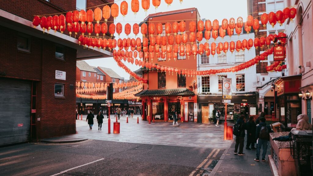 Colorful Chinatown street scene in London with traditional lanterns overhead.