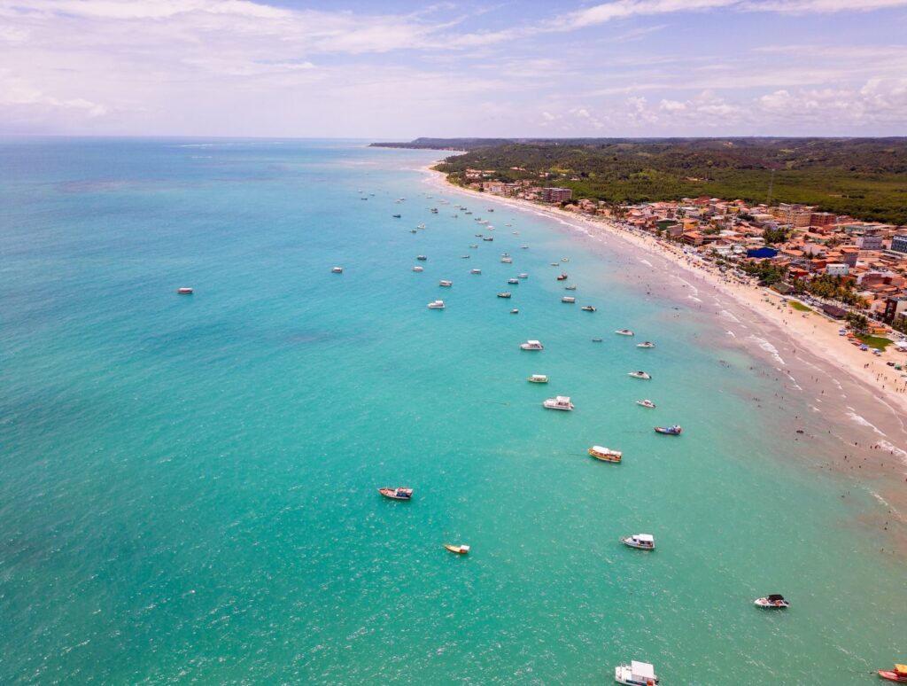 A stunning aerial view of Maragogi beach with turquoise waters and numerous boats.
