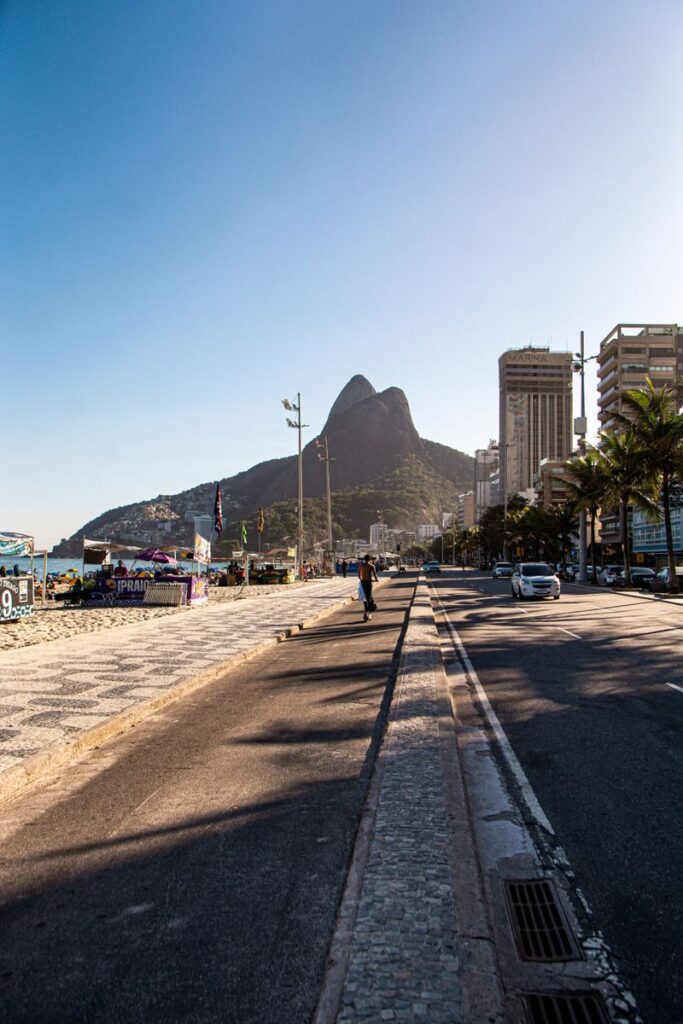 Bustling Ipanema street with view of Two Brothers Mountain under a clear sky.