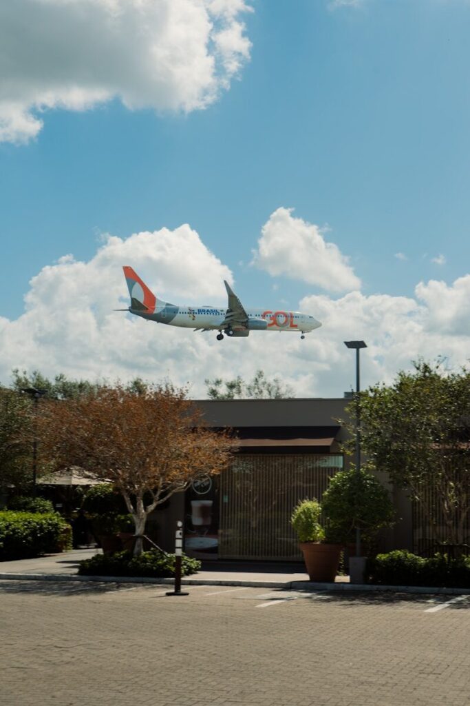 An airplane flies over a building under a blue sky.