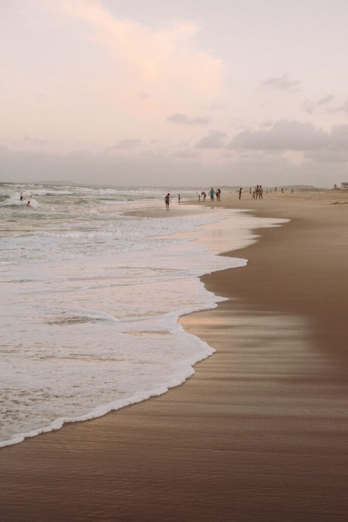 Pessoas na praia ao entardecer.