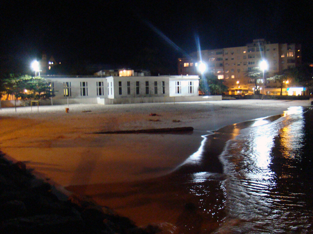 Praia noturna, edifícios, reflexos.
