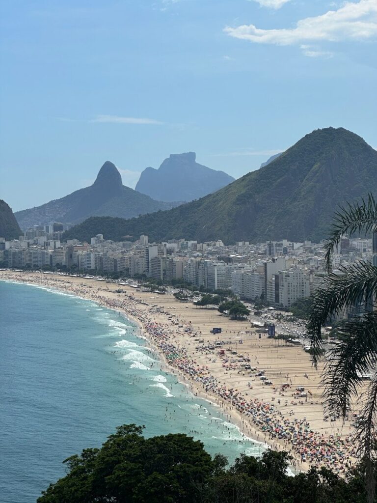 a crowded beach with mountains in the background