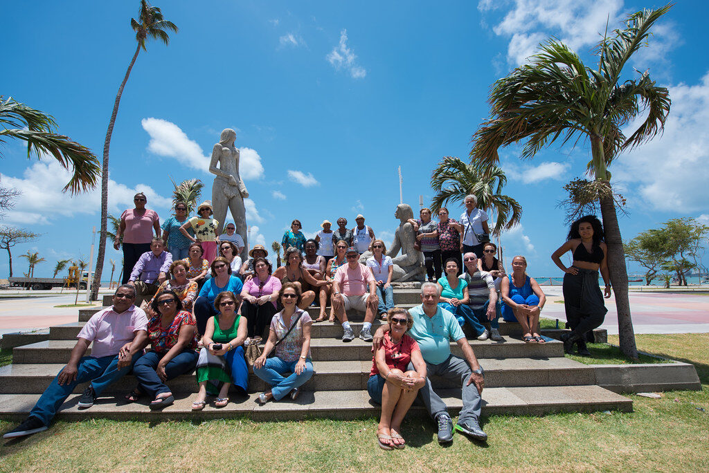 Grupo turistas estátuas palmeiras sol