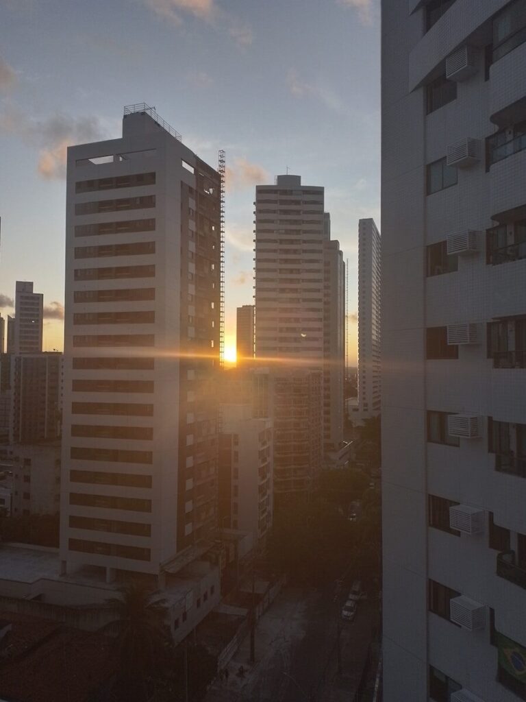 the sun is setting in a city with tall buildings